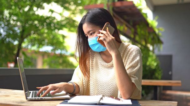 Azjatka rozmawiająca przez telefon komórkowy pracująca w domu podczas Coronavirus lub kwarantanny Covid-19 - Zdjęcie, obraz