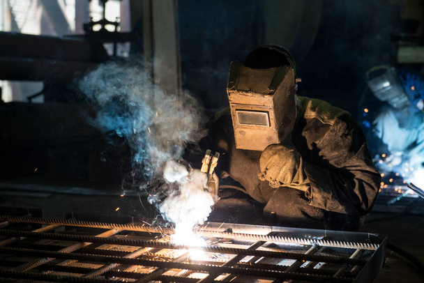 Trabajador de cerca en una máscara haciendo la soldadura en un taller
 - Foto, imagen