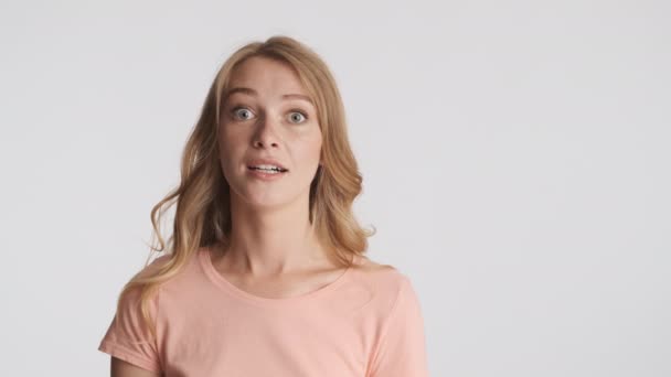 Beautiful excited woman slyly looking around over gray background. Face expression - Footage, Video