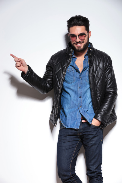 Man in leather jacket pointing finger to his side - Φωτογραφία, εικόνα