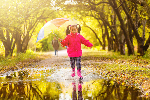 Sonbahar yağmurlu bir günde açık havada renkli şemsiyeli sevimli bir kız. - Fotoğraf, Görsel