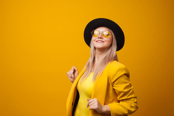 Cheerful trending young woman in bright clothes on yellow background, copy space. Cool blonde - Foto, Bild