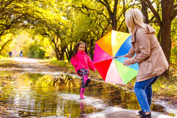 Genç anne ve küçük kızı açık havada renkli yağmurluklarla - Fotoğraf, Görsel