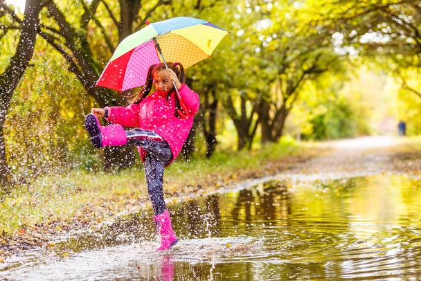Adorable toddler girl with colorful umbrella outdoors at autumn rainy day - Photo, Image