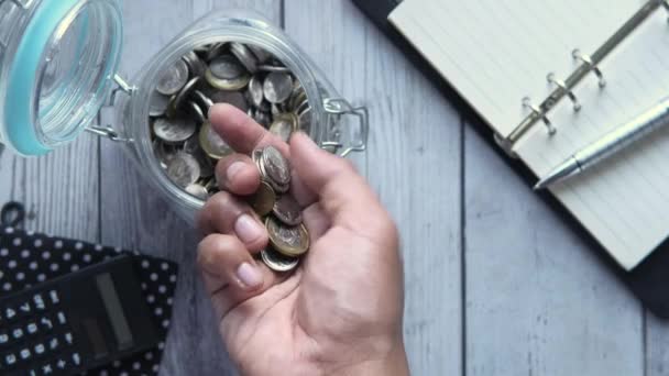 felső nézet az ember kézi megtakarítás érmék üvegben  - Felvétel, videó