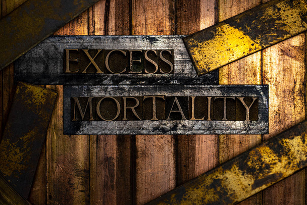 Excess Mortality text formed with real authentic typeset letters on vintage textured silver grunge copper and gold background - Photo, Image