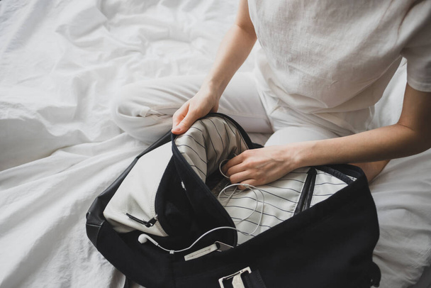 Woman packs gear, accessories in a backpack, sitting at home on the bed. High quality photo - Fotoğraf, Görsel