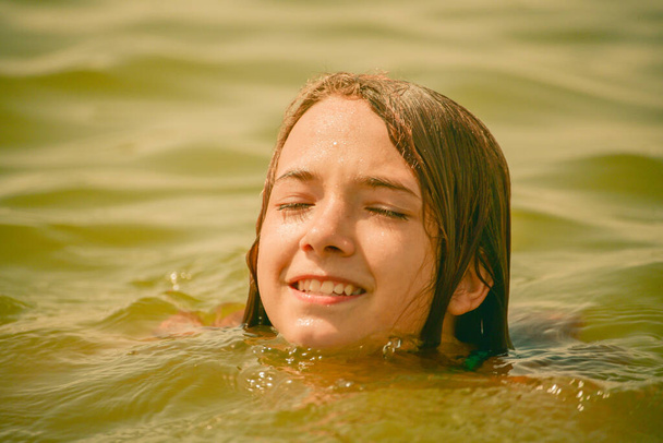 Primo piano di giovane bella ragazza in acqua. Una ragazza nuota nel river.Teenager ragazza in vacanza. Fiume, estate, nuoto, natura - Foto, immagini