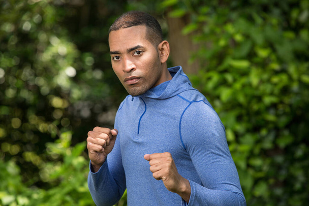 Um retrato do homem latino atlético ao ar livre com os punhos levantados, pronto para uma luta, exercícios ao ar livre
  - Foto, Imagem