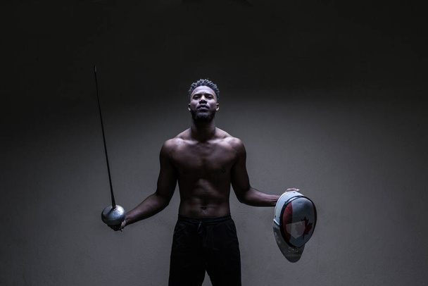 Nízký klíčový portrét kanadského atleta, držícího svou výstroj, zvedajícího ruce, koncept boje o  - Fotografie, Obrázek