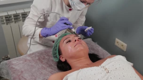 Professional cosmetologist woman doing ultrasonic face cleaning to patient. - Footage, Video