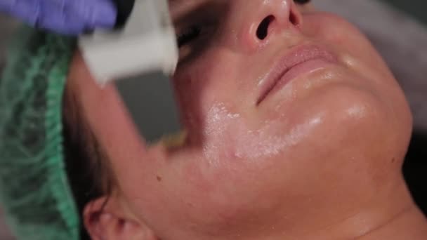 Cosmetóloga profesional haciendo limpieza facial ultrasónica al paciente. - Metraje, vídeo
