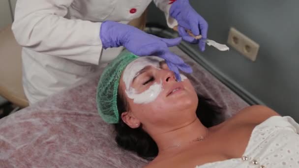 Professionele schoonheidsspecialiste brengt een masker aan op het gezicht. - Video