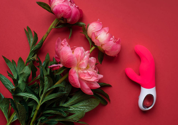 Sex toy. Vibrator for women. Space for text. Red. Pink flowers. - Foto, afbeelding