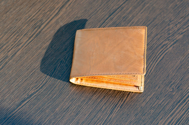 Nahka ruskea lompakko ruskealla taustalla. Säteet auringon paistaa lompakossa - Valokuva, kuva