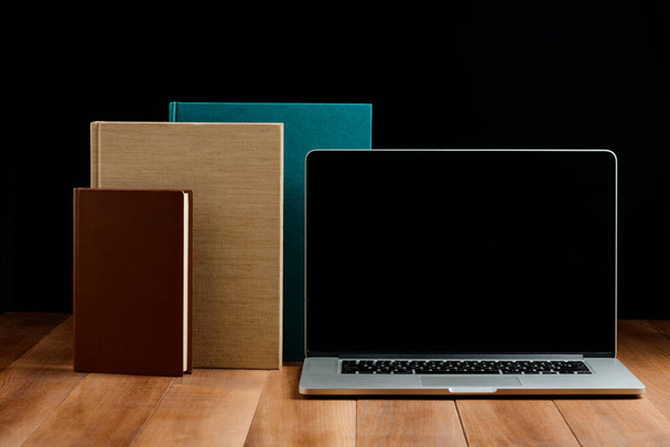 Hardcover books and laptop on wooden desktop - Fotografie, Obrázek