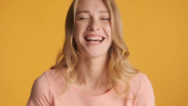 Porträt eines hübschen blonden Mädchens, das glücklich in die Kamera vor buntem Hintergrund blickt. Netter Ausdruck - Filmmaterial, Video