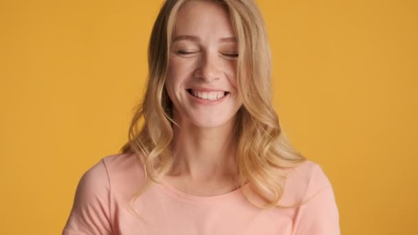Pěkný roztomilý blond dívka šťastně dívá do kamery a usmívá se přes barevné pozadí - Záběry, video