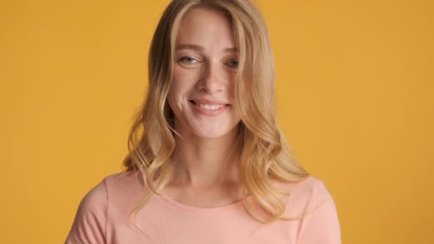 Attraktives blondes Mädchen, das glücklich in die Kamera über bunten Hintergrund blickt. Lächelnder Ausdruck - Filmmaterial, Video