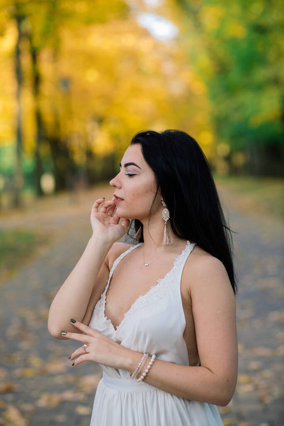Joven hermosa morena hembra en vestido blanco largo en el parque de otoño. - Foto, imagen