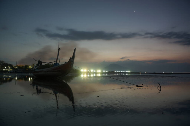 Vissersboot aan de kust bij zonsondergang - Foto, afbeelding