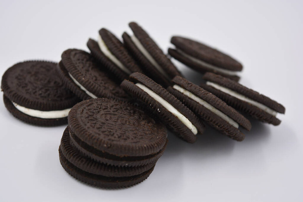 Chocolate Black Thin Cookie mit weißer Füllung, köstliche Milch Oreo Cookie auf weißem Hintergrund verstreut. - Foto, Bild