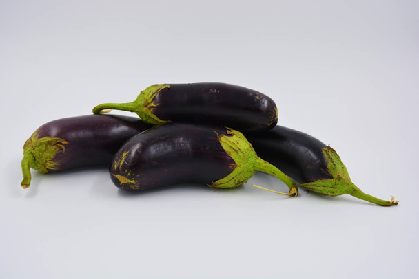 Berenjenas frescas de color azul púrpura recientemente recogidas y dispuestas sobre un fondo blanco mate. Deliciosas verduras que crecen en Ucrania, comida sana y saludable para todos los días. - Foto, imagen