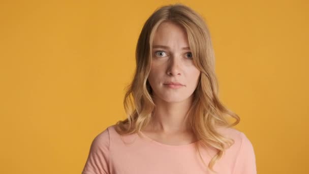 Jeune femme blonde offensée montrant tristement la langue à la caméra sur fond coloré - Séquence, vidéo