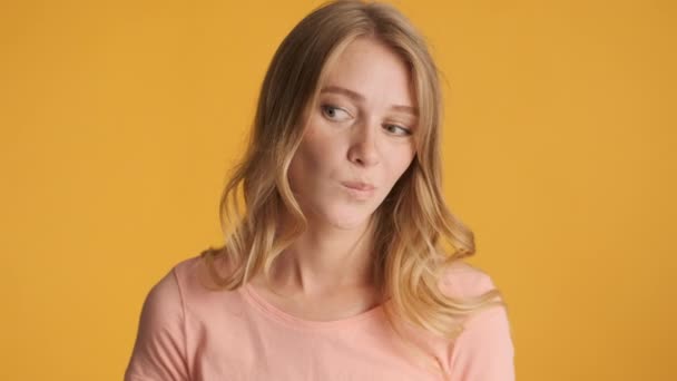 Young doubting blond woman  pondering posing on camera over colorful background. Need to think expression - Filmagem, Vídeo