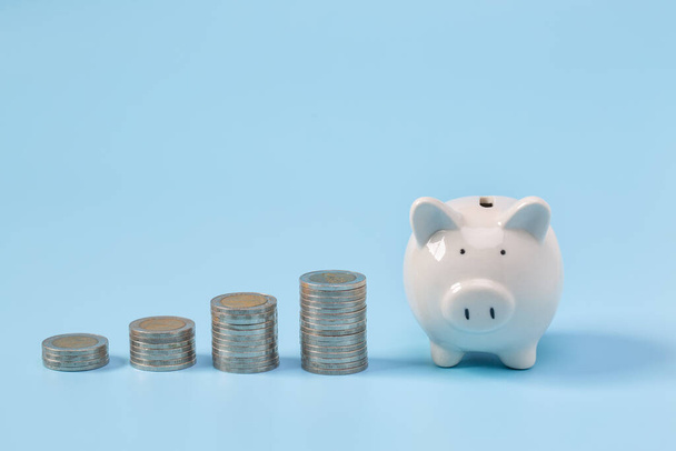 Piggy banco com moedas de crescimento em um fundo azul, o que significa grwoth conceito de sucesso de negócios
 - Foto, Imagem