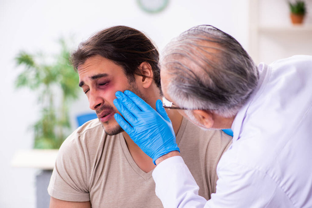 Jeune visage blessé homme visitant expérimenté médecin traumato - Photo, image