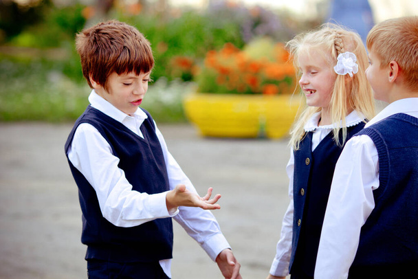 Back to school: three school children (boys and a girl) wearing uniform playing and laughing outdoors - Foto, afbeelding