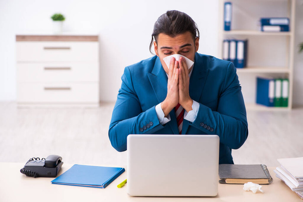 Sick male employee suffering at workplace from coronavirus - Фото, изображение