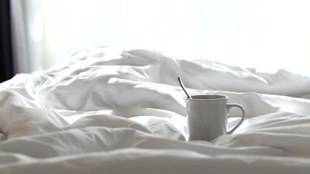 Witte koffiemokken en rook die opstijgt uit de mokken lagen op het bed met de ochtendzon. - Video