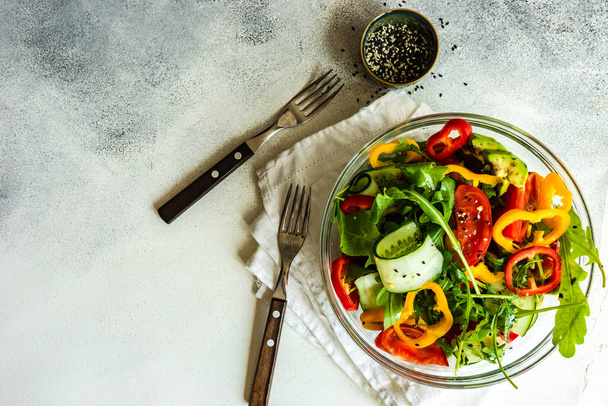 Healthy vegetable salad with aragula,  avocado and sesame seeds on concrete background with copy space - Zdjęcie, obraz