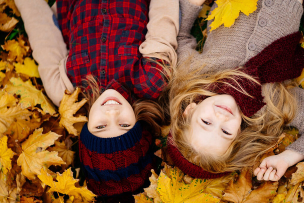 little girls in hat lying on yellow autumn leaves. - Фото, изображение