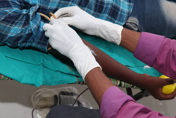 Ο άνθρωπος δίνει αιμοδοσία με βελόνα στο χέρι του. αρχική εικόνα για Παγκόσμια ημέρα αιμοδοσίας-14 Ιουνίου. - Φωτογραφία, εικόνα