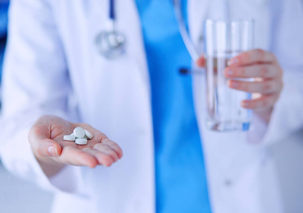 Close-up shot of doctors hands holding pills and glass of water. - Valokuva, kuva