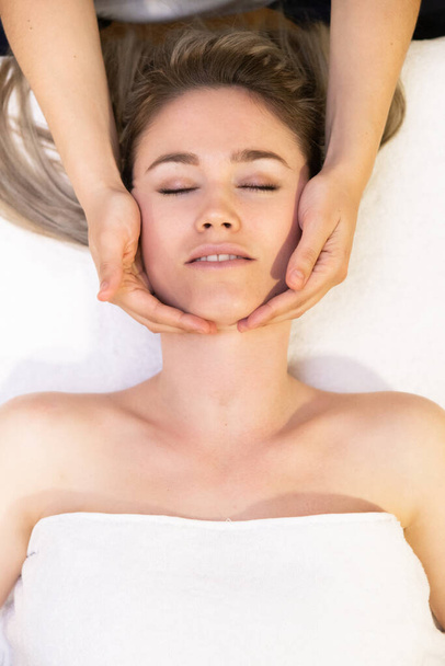 Young blond woman receiving a head massage in a spa center. - Φωτογραφία, εικόνα