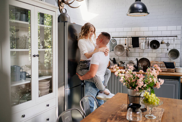 pair of lovers kissing and hugging in kitchen next to the refrigerator. - Foto, Bild