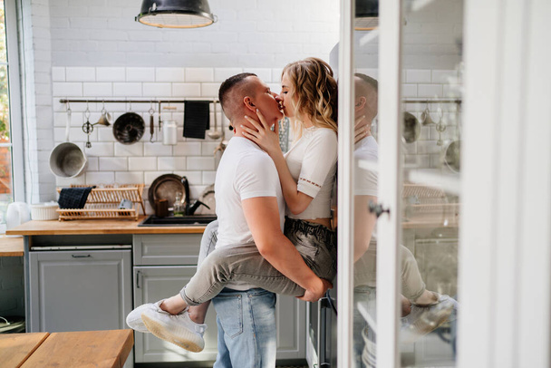 pair of lovers kissing and hugging in kitchen next to the refrigerator. - Φωτογραφία, εικόνα