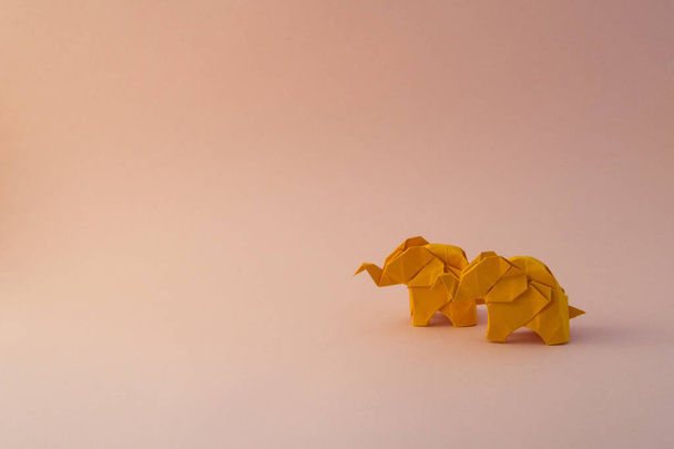 Origami elephants made of colour paper on green background. Paper and forest conservation concept. Family and childhood. Mockup, copy space. - Foto, immagini
