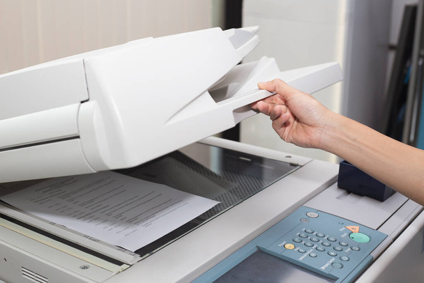 woman hands putting a sheet of paper into a copying device or printer in the office - Foto, immagini