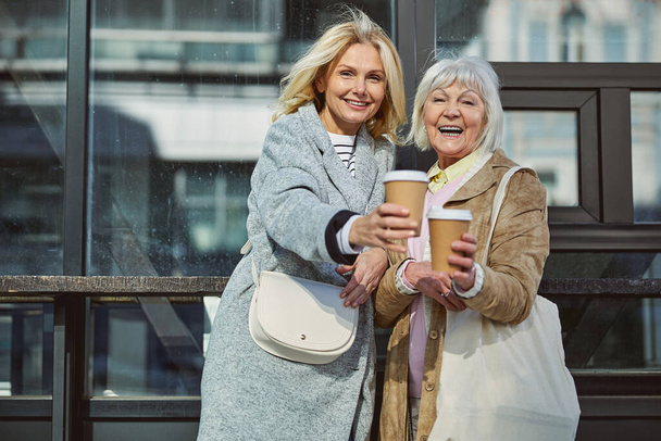 Beautiful mature women with coffee posing at the photo camera - Fotoğraf, Görsel