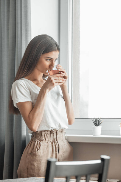 Bella donna che beve tè mattutino dietro la finestra. Sfida di un nuovo giorno. Copia spazio - Foto, immagini