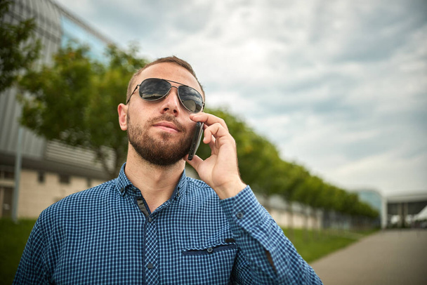 Traveler guy calling on mobile phone. Portrait of confident young businessman - Fotó, kép
