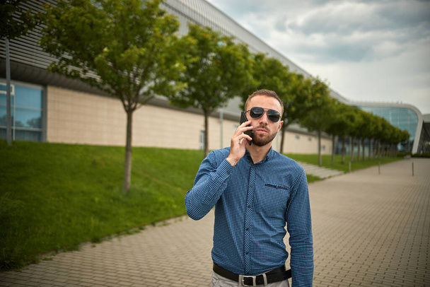 Traveler guy calling on mobile phone. Portrait of confident young businessman - Fotó, kép