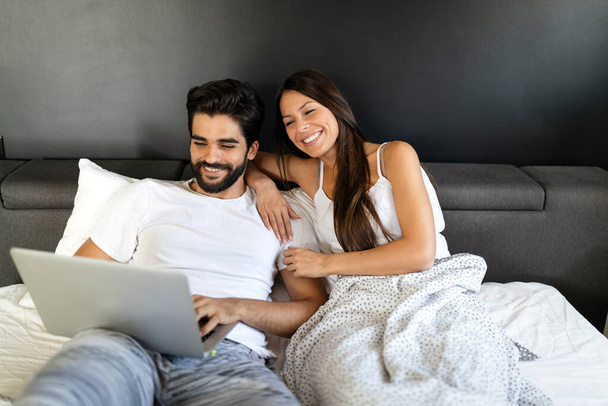 Young happy smiling couple with laptop at bedroom - Foto, Imagem