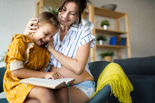 Mother with her pretty daughter reading a book at home - Foto, immagini