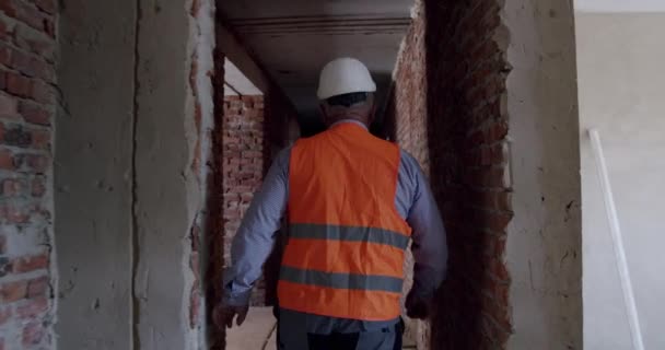 Following Shot of unrecognized Professional Factory Worker Wearing Hard Hat Walking Thorugh construction - Filmmaterial, Video